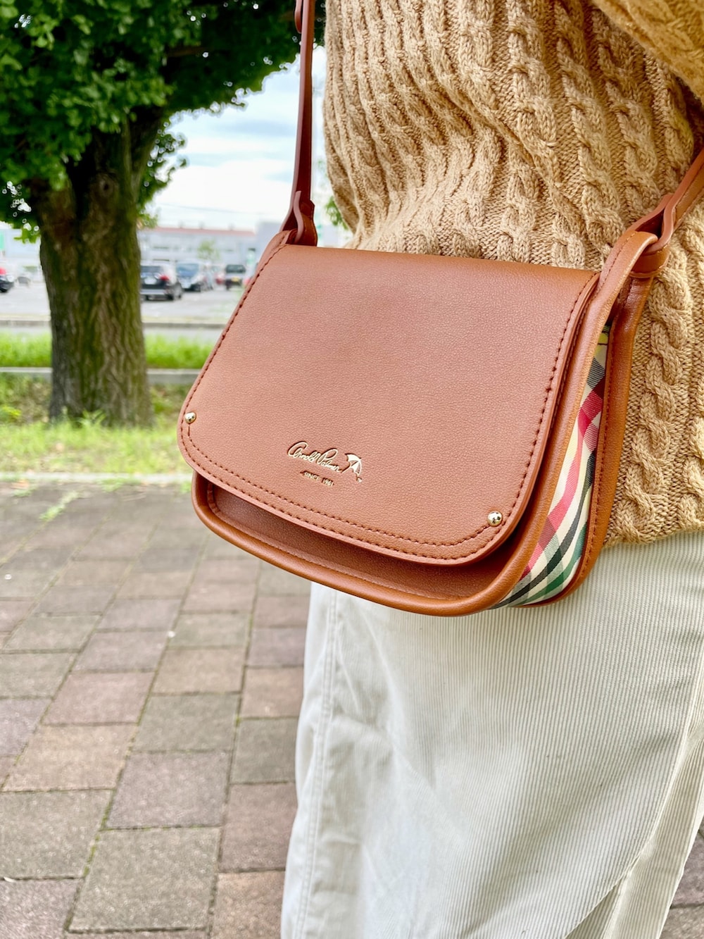 ブラウン系のショルダーバッグ、イエロー系のカーディガン/ボレロ、ホワイト系のスニーカーを着用したレディースの秋コーディネートの4枚目の写真