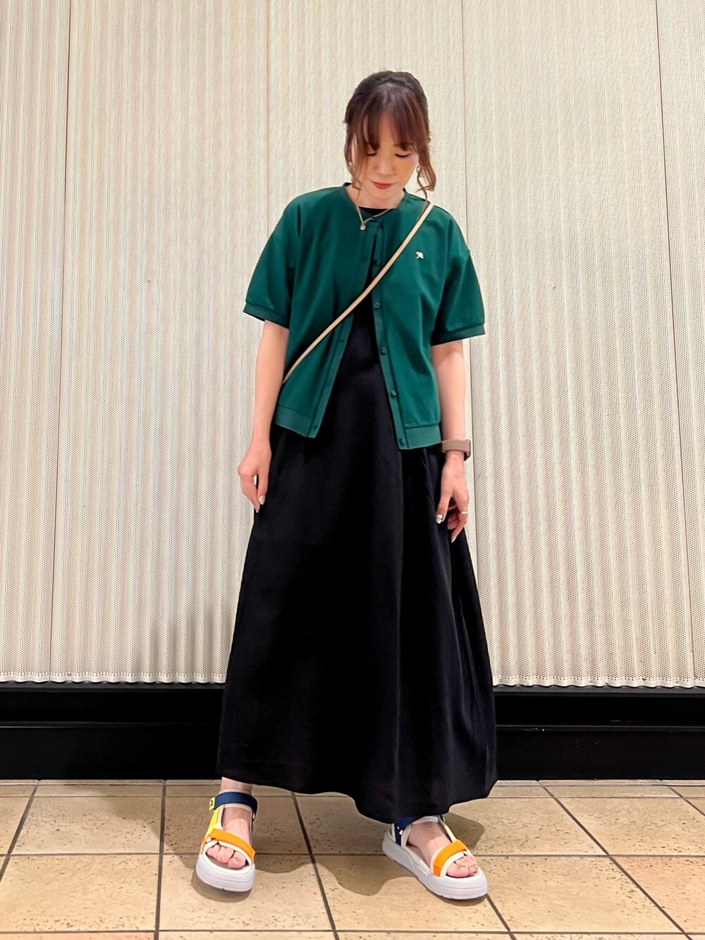 ブラック系のワンピース、ベージュ系のショルダーバッグ、グリーン系のカーディガン/ボレロを着用したレディースの春コーディネートの6枚目の写真