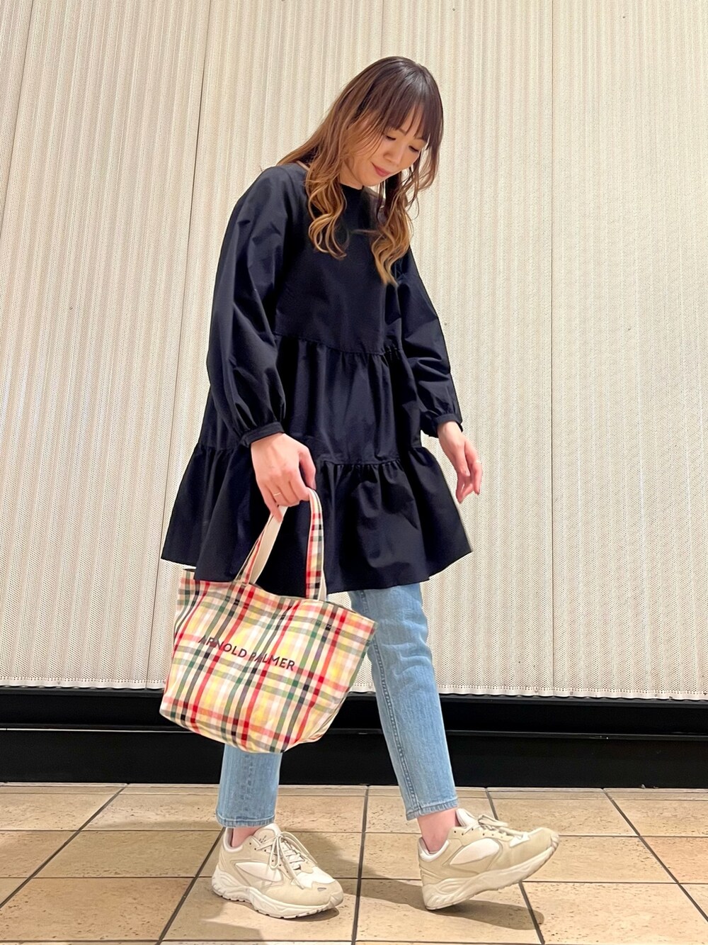 ブルー系のデニムパンツ、ブラック系のチュニック、ベージュ系のトートバッグを着用したレディースの春コーディネートの2枚目の写真