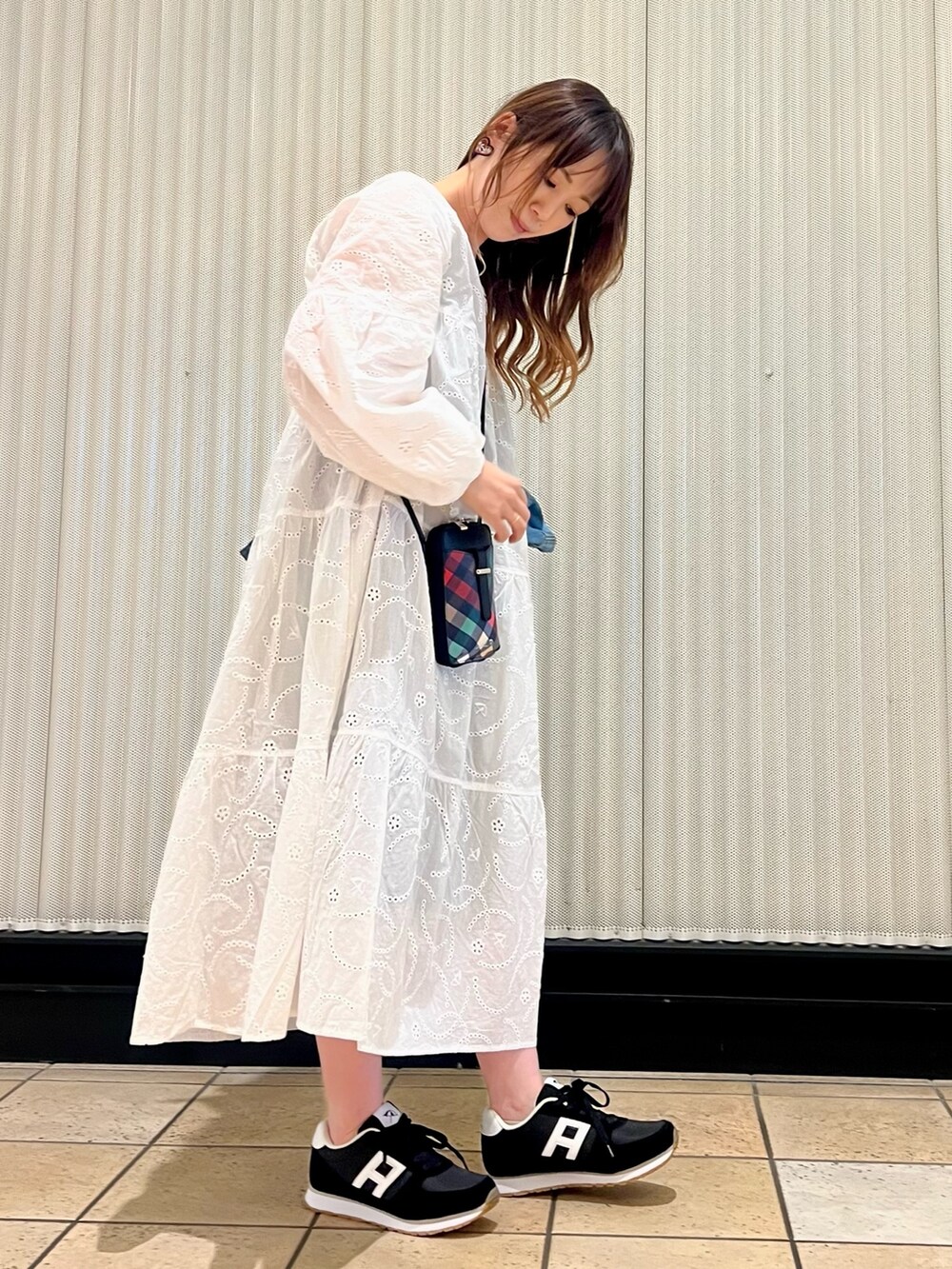 ブラック系のショルダーバッグ、ブラック系のスニーカー、ブルー系のデニムジャケットを着用したレディースの春コーディネートの4枚目の写真