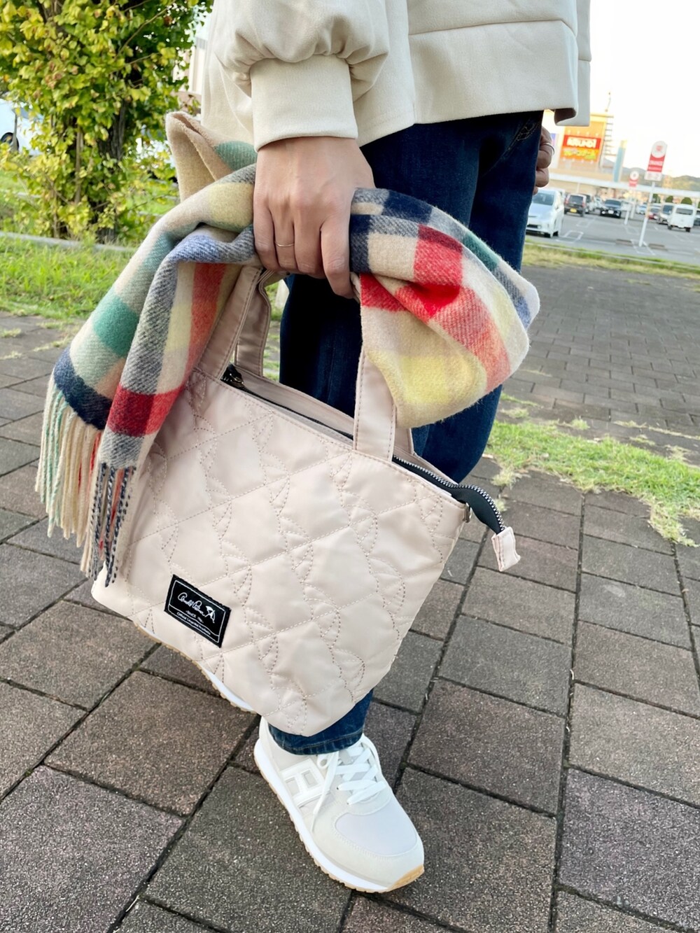 グレー系のスニーカー、ホワイト系のトートバッグ、ブルー系のデニムパンツを着用したレディースの秋コーディネートの6枚目の写真