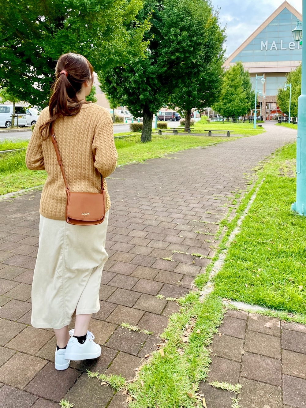 ブラウン系のショルダーバッグ、イエロー系のカーディガン/ボレロ、ホワイト系のスニーカーを着用したレディースの秋コーディネートの3枚目の写真