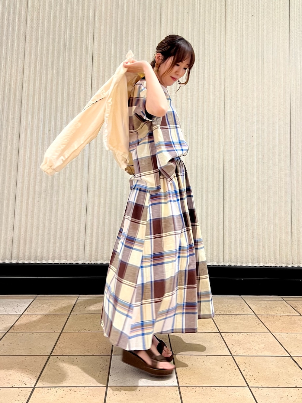 ベージュ系のショルダーバッグ、ブラウン系のサンダル、ホワイト系のナイロンジャケットを着用したレディースの春コーディネートの3枚目の写真