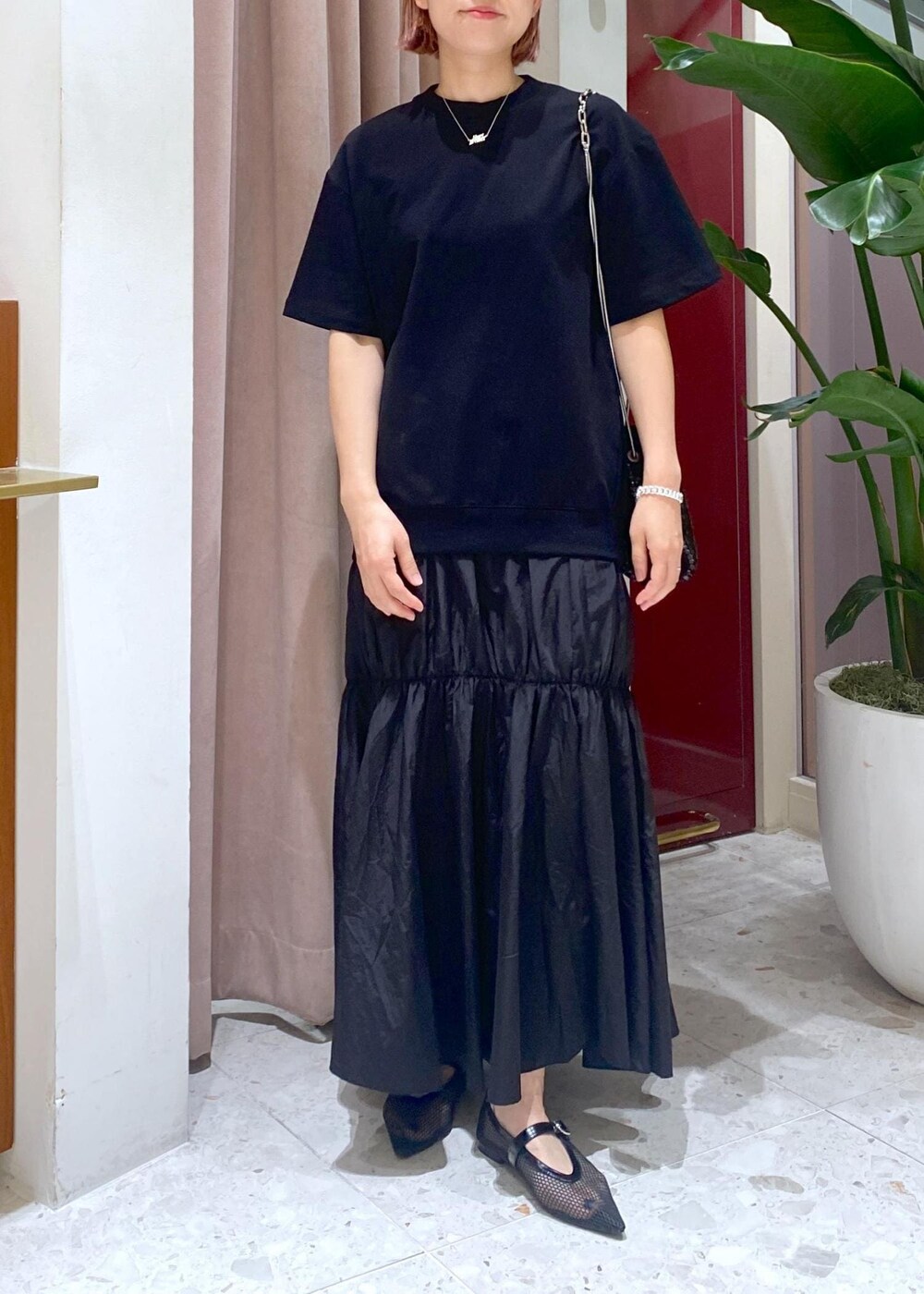 ブラック系のハンドバッグ、ブラック系のパンプス、ブラック系のワンピースを着用したレディースの夏コーディネートの2枚目の写真
