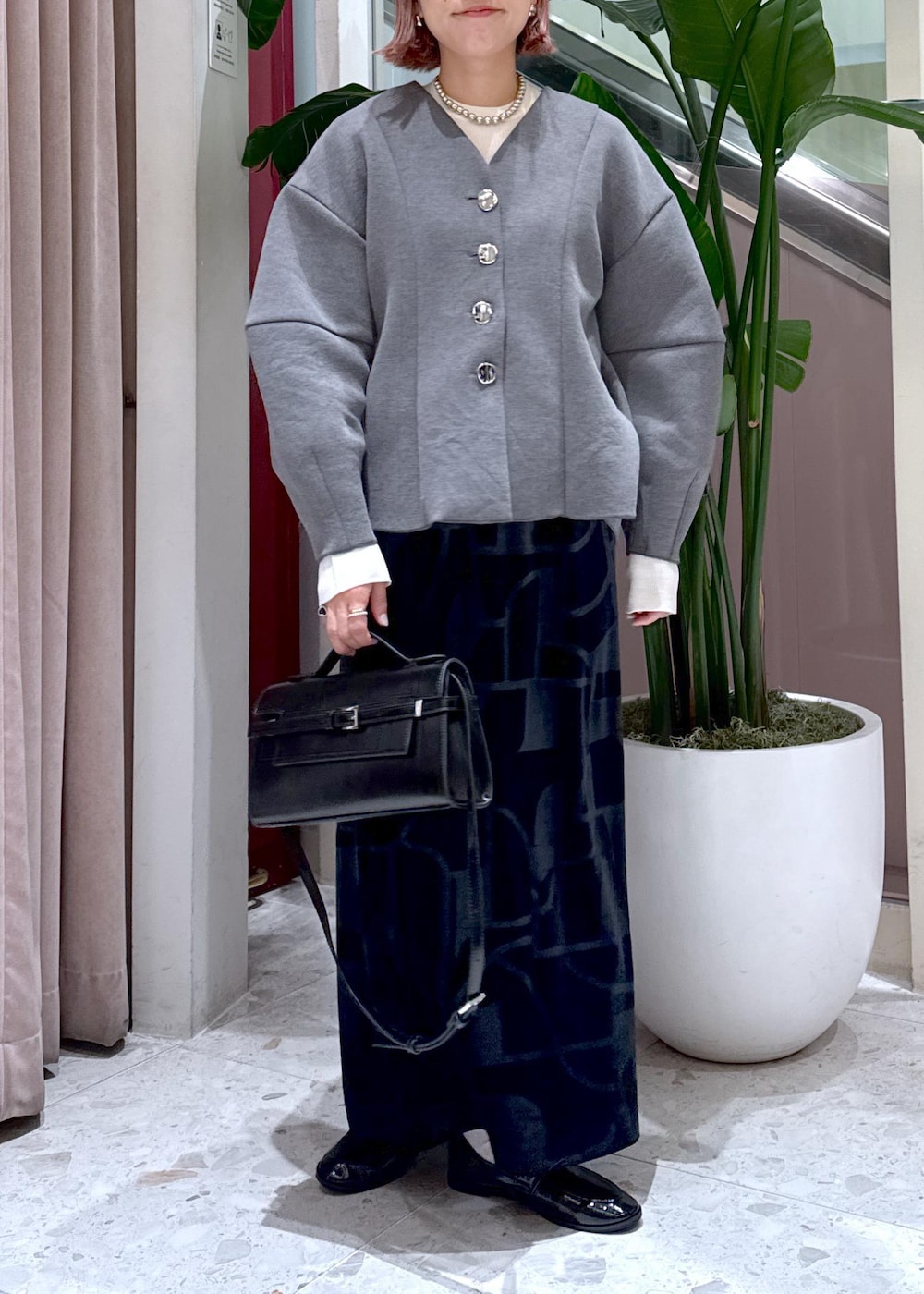 ブラック系のローファー、ブラック系のスカート、グレー系のカーディガン/ボレロを着用したレディースの秋コーディネートの10枚目の写真