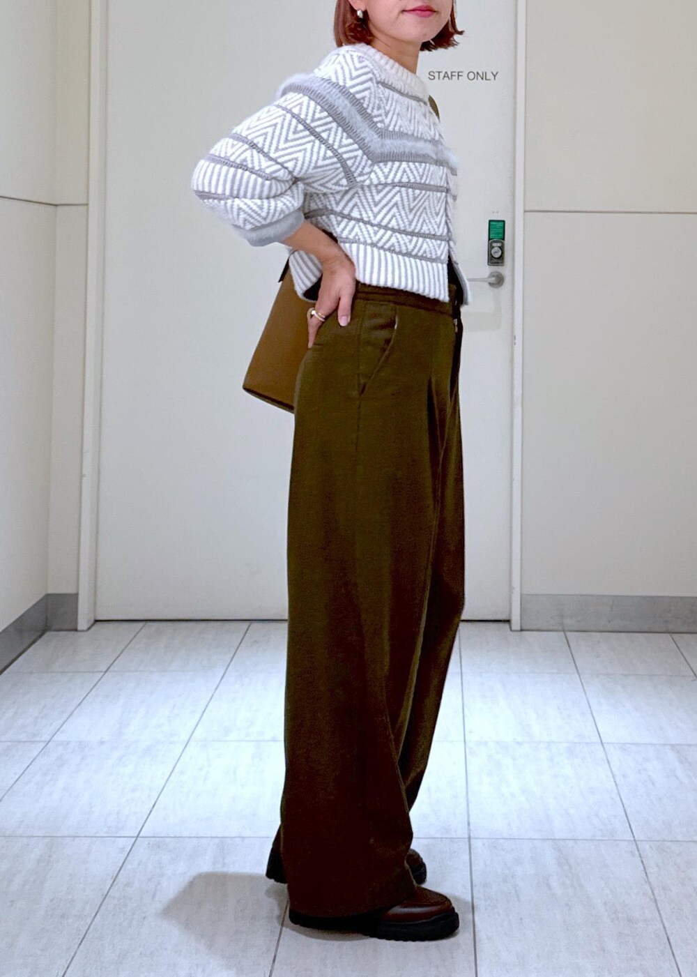 ホワイト系のカーディガン/ボレロ、グリーン系のスラックス、ブラウン系のハンドバッグを着用したレディースの秋コーディネートの7枚目の写真