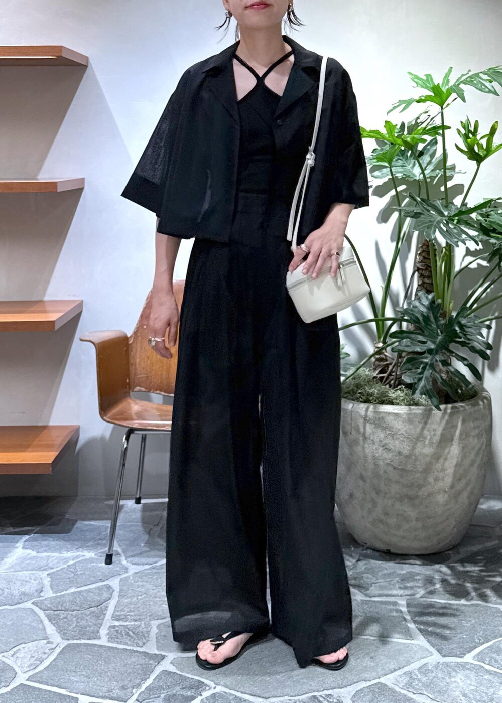 ホワイト系のショルダーバッグ、ブラック系のキャミソール、ブラック系のスラックスを着用したレディースの夏コーディネートの2枚目の写真