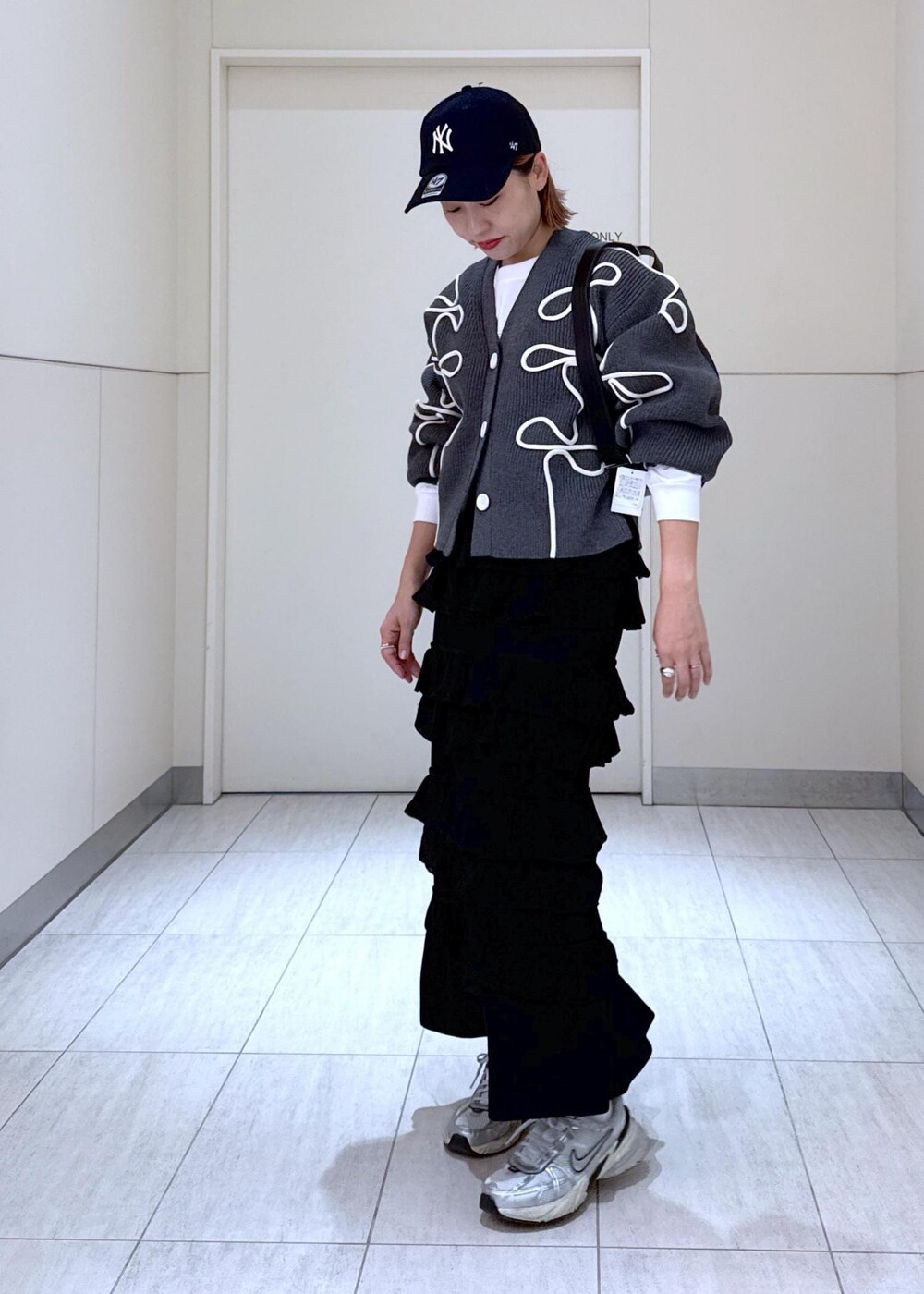 ホワイト系のTシャツ/カットソー、ブラック系のスカート、グレー系のカーディガン/ボレロを着用したレディースの秋コーディネートの3枚目の写真