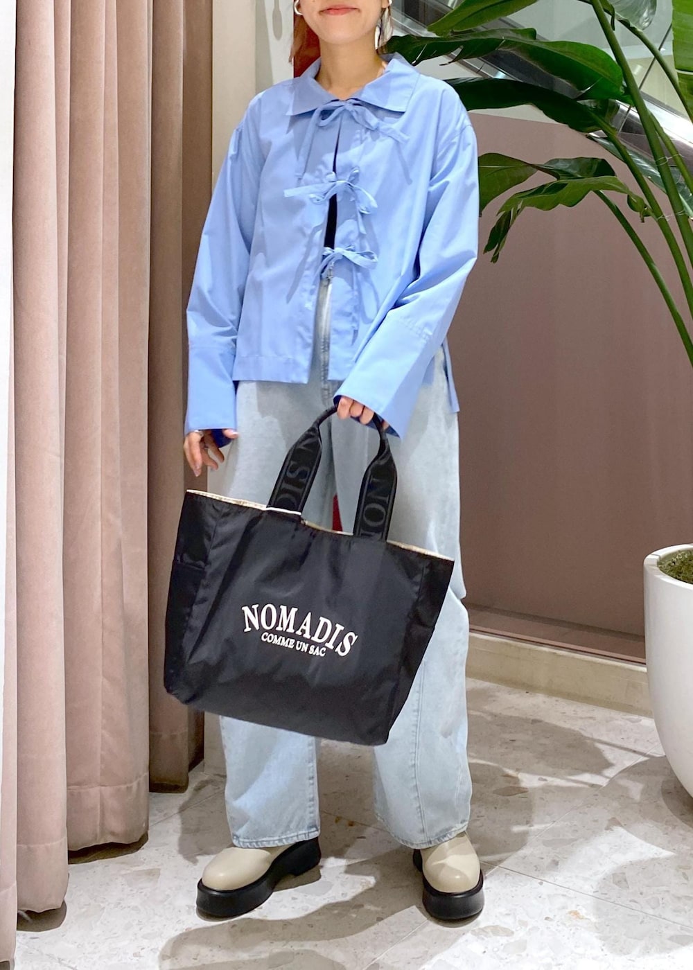 ブルー系のデニムパンツ、ブラック系のトートバッグ、ベージュ系のサンダルを着用したレディースの秋コーディネートの6枚目の写真