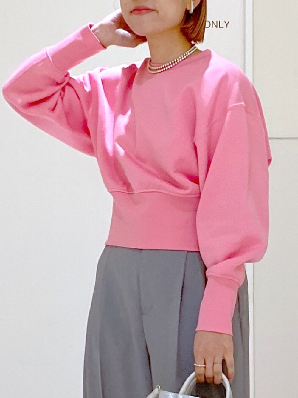 ピンク系のスウェット、グレー系のスラックス、シルバー系のショルダーバッグを着用したレディースの冬コーディネートの7枚目の写真