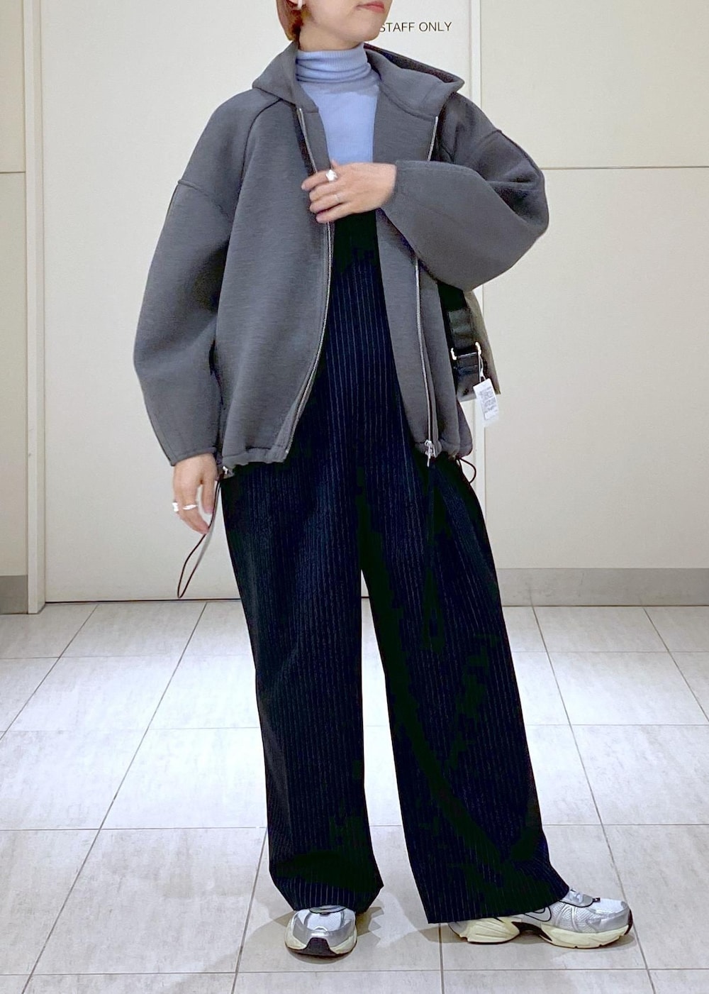 ブルー系のニット/セーター、グレー系のブルゾン、ブラック系のショルダーバッグを着用したレディースの冬コーディネートの2枚目の写真