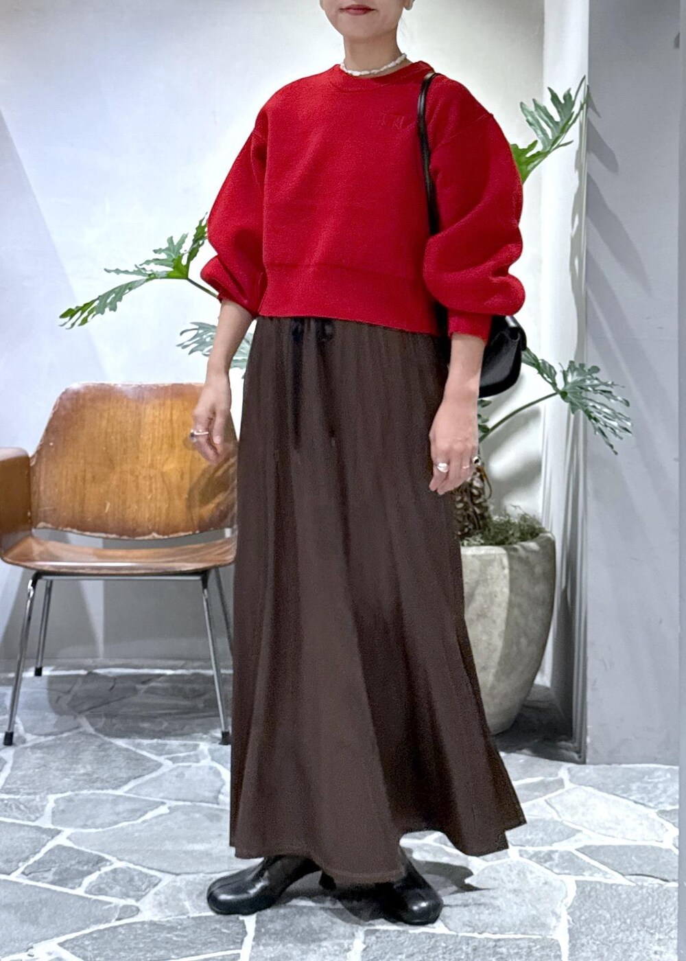 ブラック系のブーツ、ブラウン系のスカート、レッド系のニット/セーターを着用したレディースの秋コーディネートの2枚目の写真