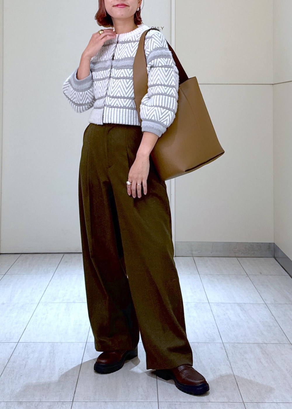 ホワイト系のカーディガン/ボレロ、グリーン系のスラックス、ブラウン系のハンドバッグを着用したレディースの秋コーディネートの3枚目の写真