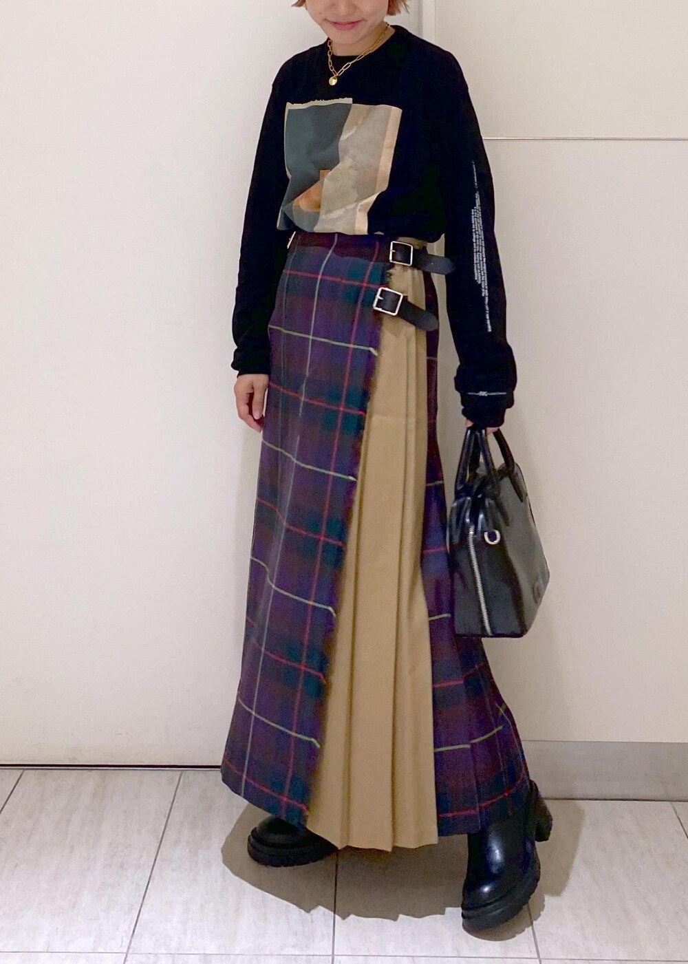 ブラック系のボストンバッグ、ブラック系のブーツ、パープル系のスカートを着用したレディースの秋コーディネートの4枚目の写真