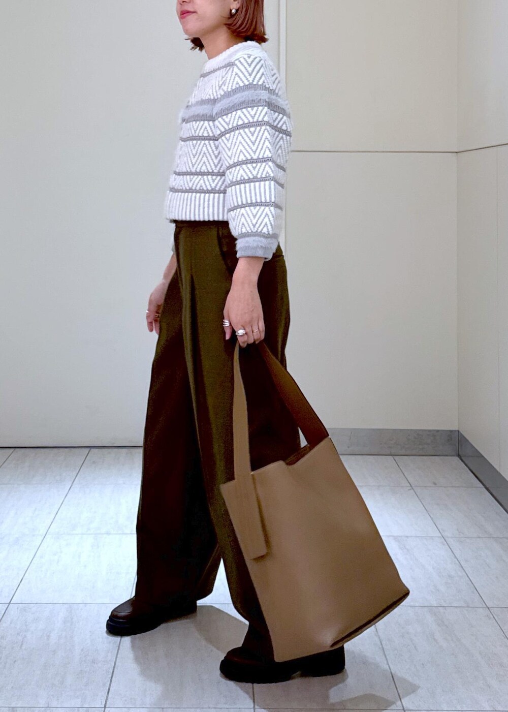 ホワイト系のカーディガン/ボレロ、グリーン系のスラックス、ブラウン系のハンドバッグを着用したレディースの秋コーディネートの6枚目の写真
