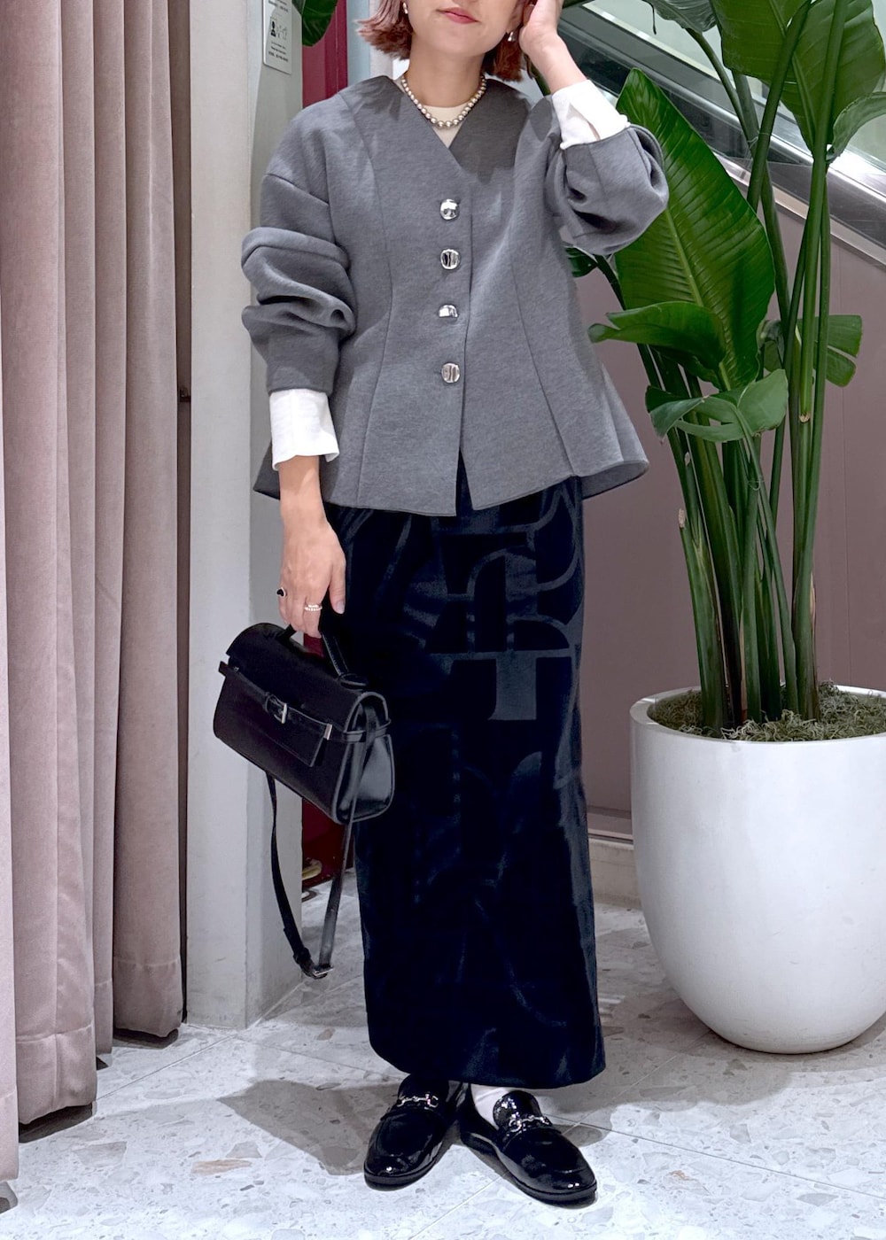 ブラック系のローファー、ブラック系のスカート、グレー系のカーディガン/ボレロを着用したレディースの秋コーディネートの4枚目の写真