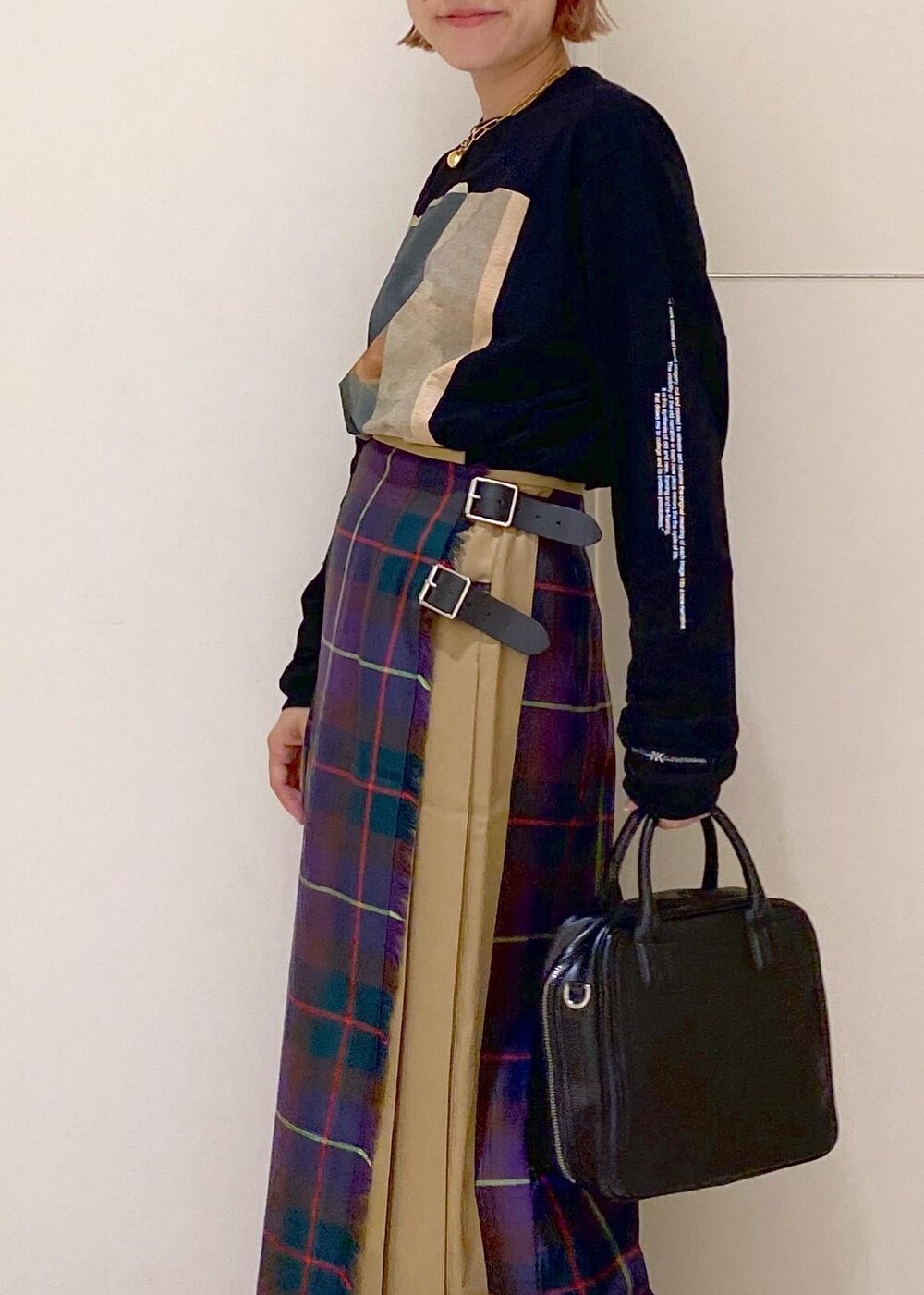 ブラック系のボストンバッグ、ブラック系のブーツ、パープル系のスカートを着用したレディースの秋コーディネートの6枚目の写真