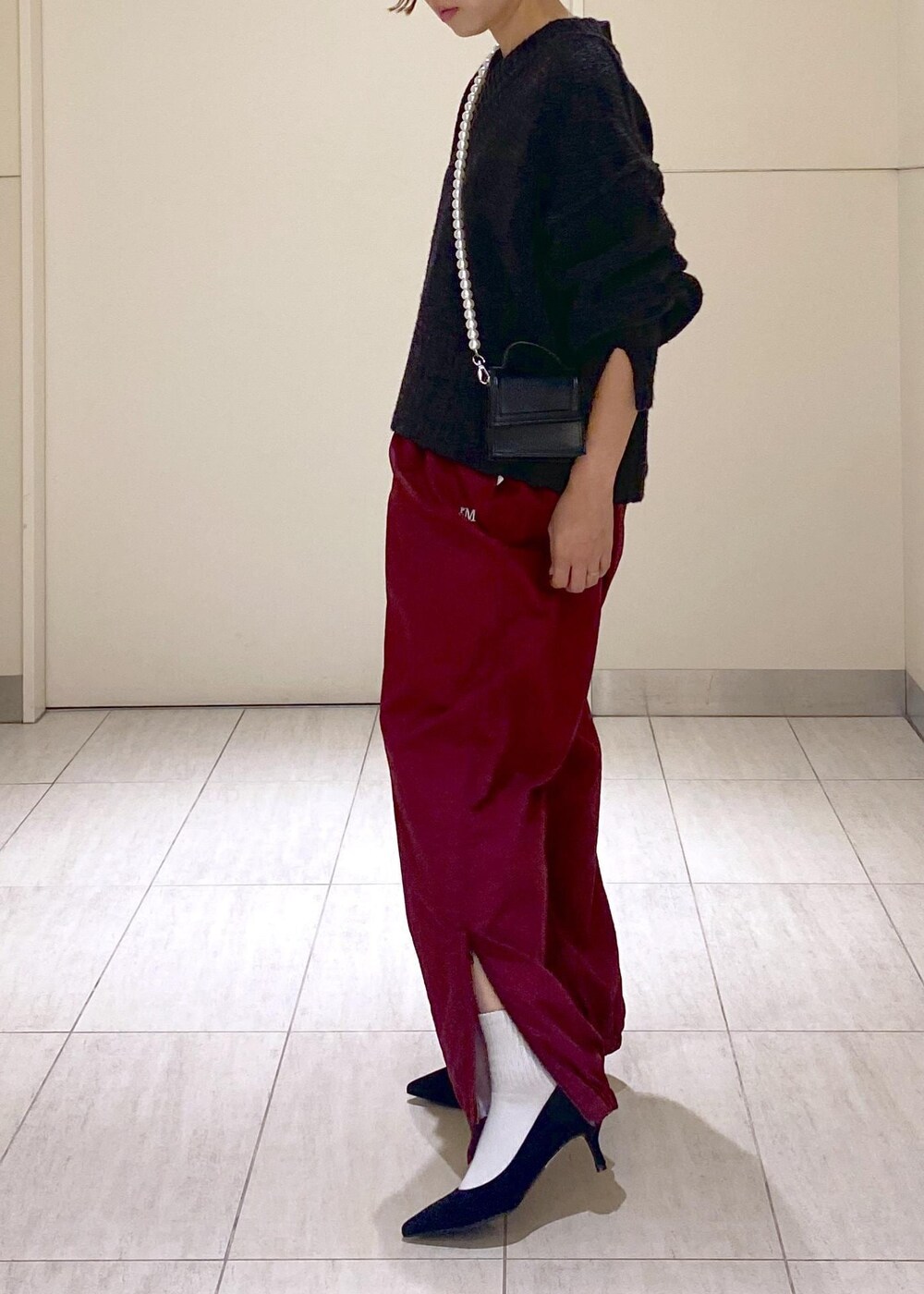 ブラック系のニット/セーター、ブラック系のショルダーバッグ、レッド系のその他パンツを着用したレディースの秋コーディネートの8枚目の写真