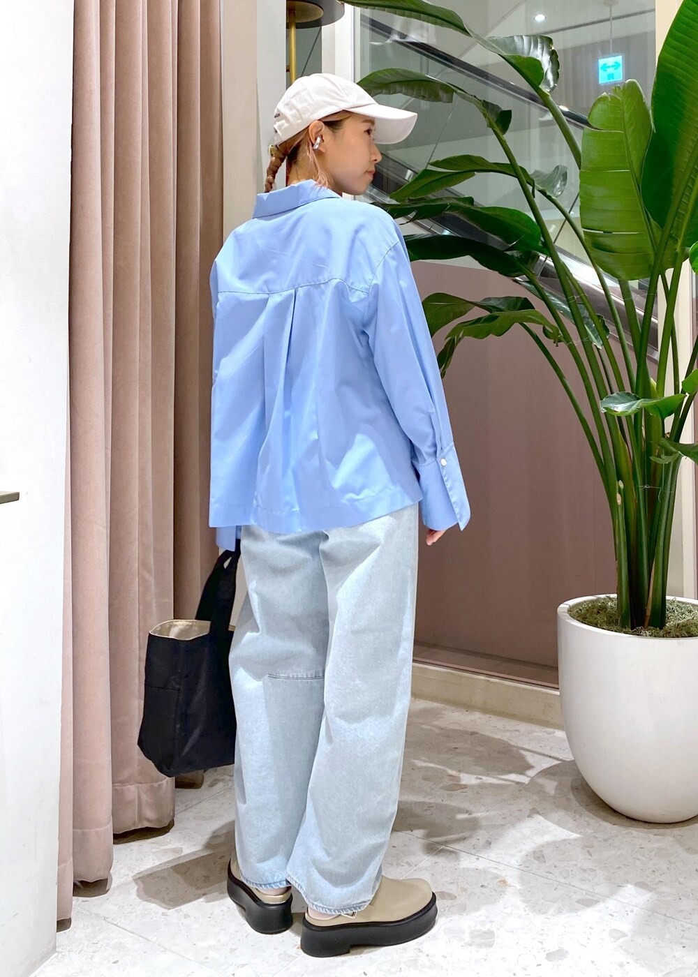 ブルー系のデニムパンツ、ブラック系のトートバッグ、ベージュ系のサンダルを着用したレディースの秋コーディネートの5枚目の写真