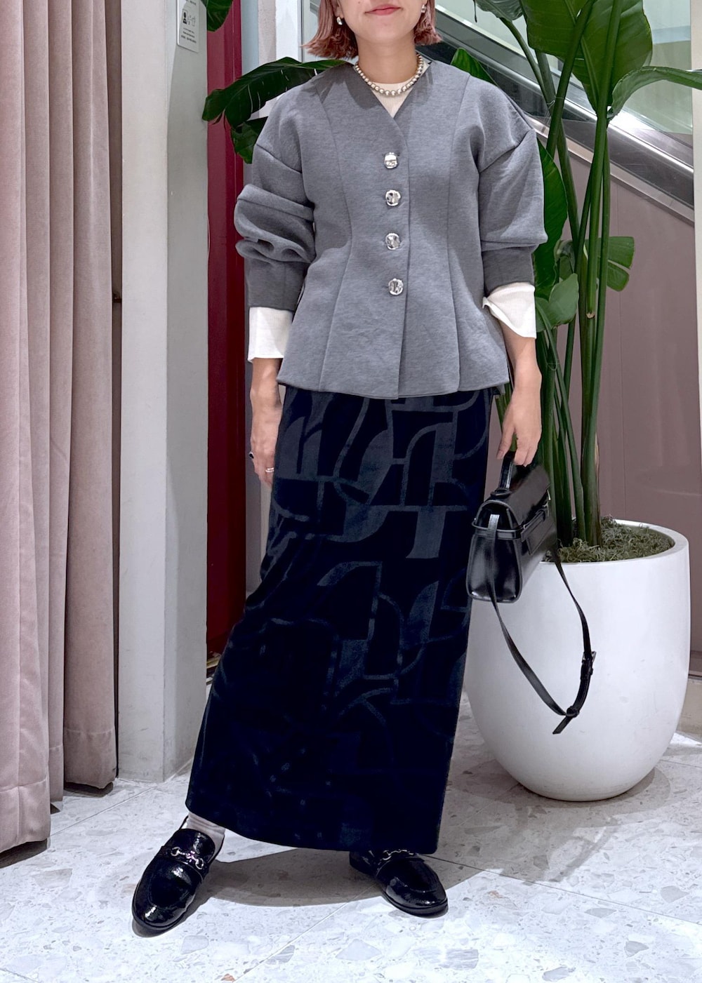 ブラック系のローファー、ブラック系のスカート、グレー系のカーディガン/ボレロを着用したレディースの秋コーディネートの3枚目の写真