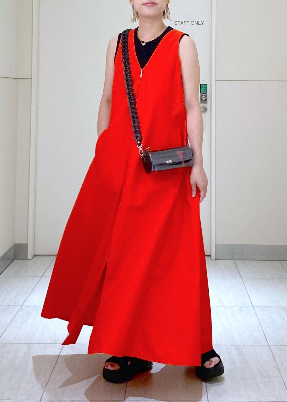 ブラック系のサンダル、ブラック系のドラムバッグ、レッド系のワンピースを着用したレディースの夏コーディネートの2枚目の写真