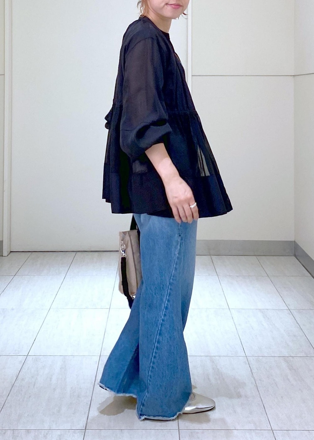 ブルー系のデニムパンツ、シルバー系のバレエシューズ、ブラック系のTシャツ/カットソーを着用したレディースの夏コーディネートの3枚目の写真