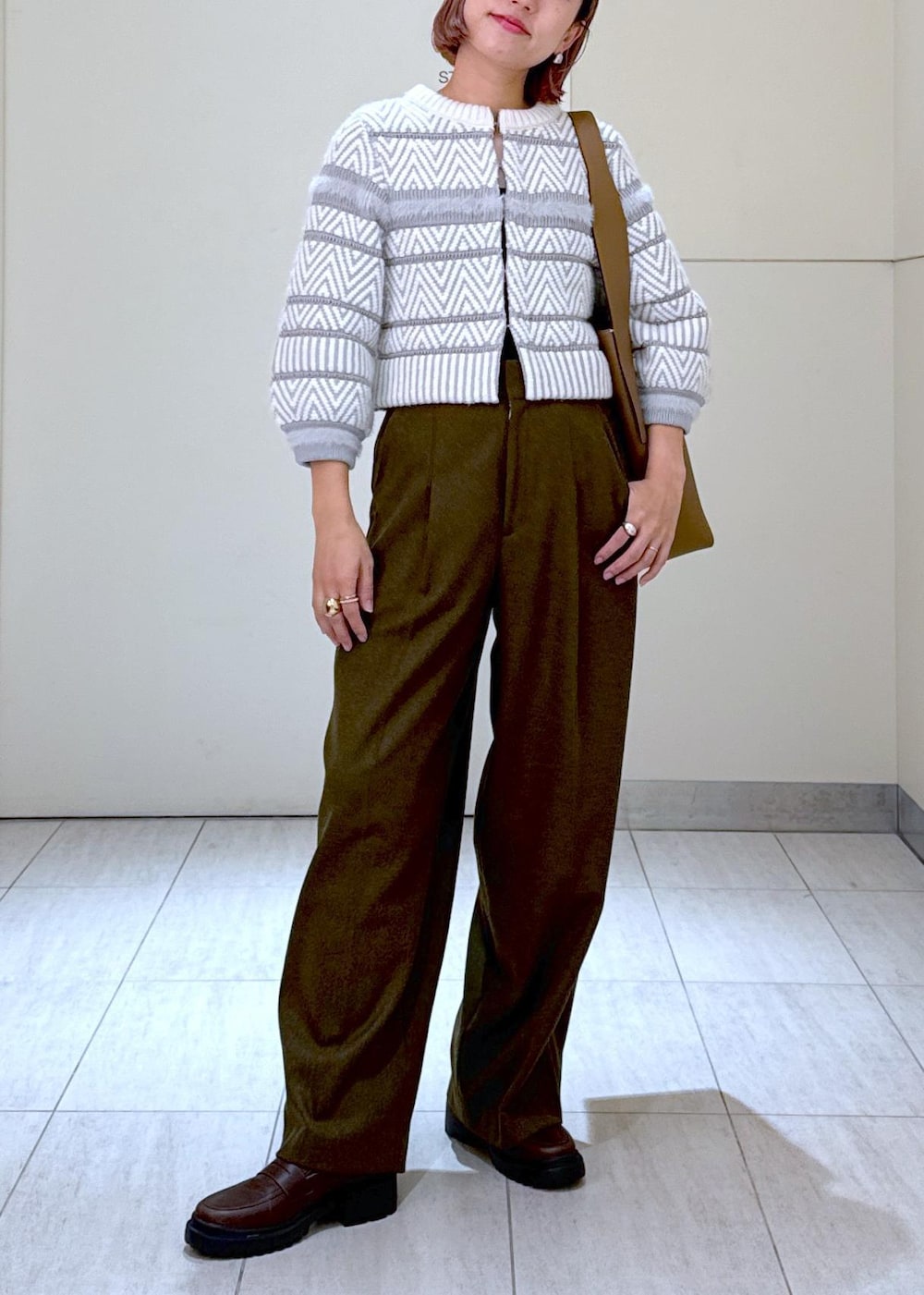 ホワイト系のカーディガン/ボレロ、グリーン系のスラックス、ブラウン系のハンドバッグを着用したレディースの秋コーディネートの2枚目の写真