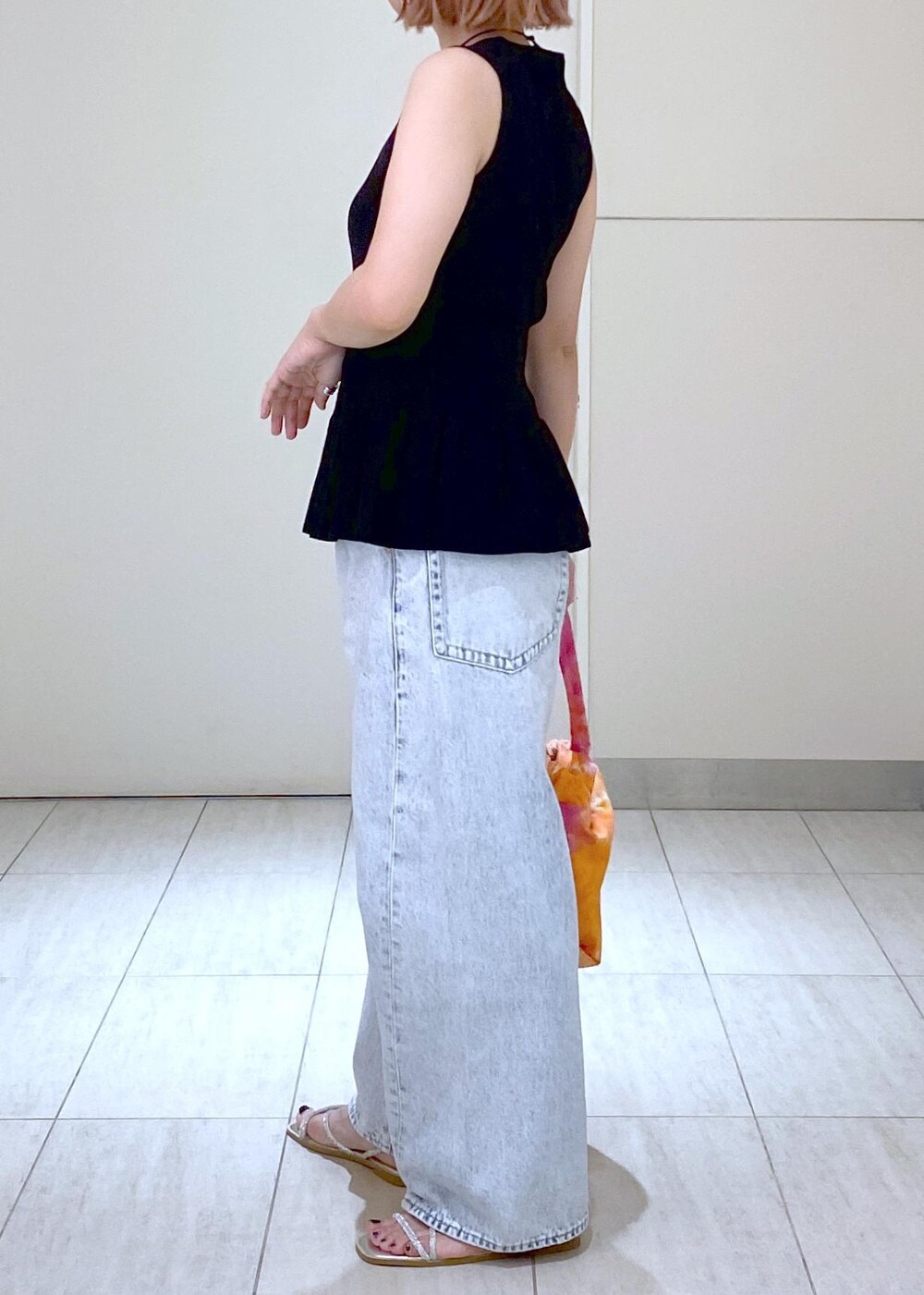 シルバー系のサンダル、ブラック系のニット/セーター、ブルー系のデニムパンツを着用したレディースの春コーディネートの4枚目の写真