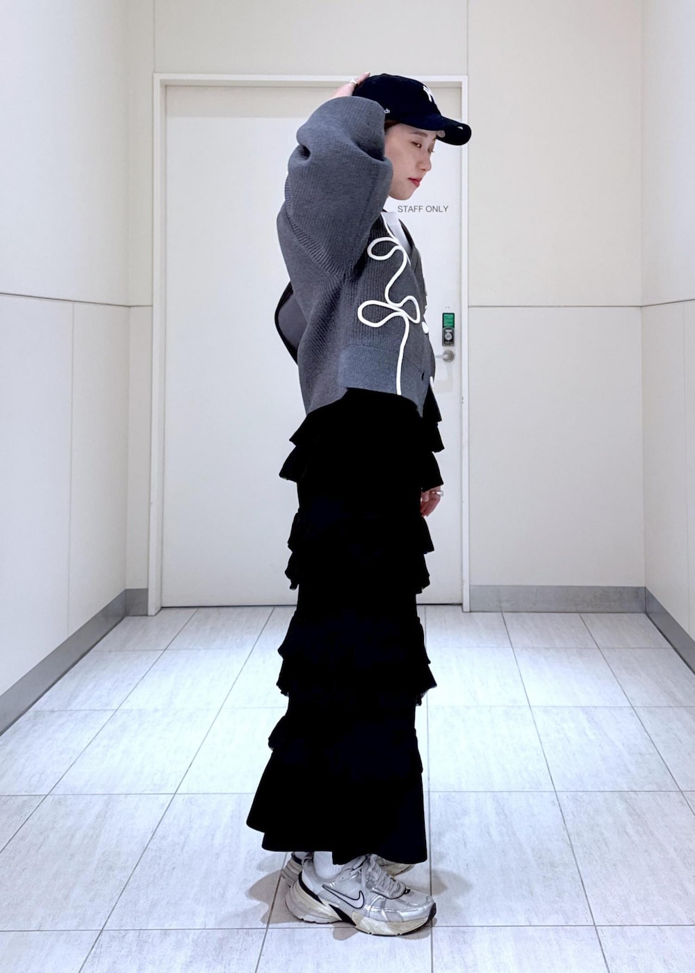 ホワイト系のTシャツ/カットソー、ブラック系のスカート、グレー系のカーディガン/ボレロを着用したレディースの秋コーディネートの7枚目の写真