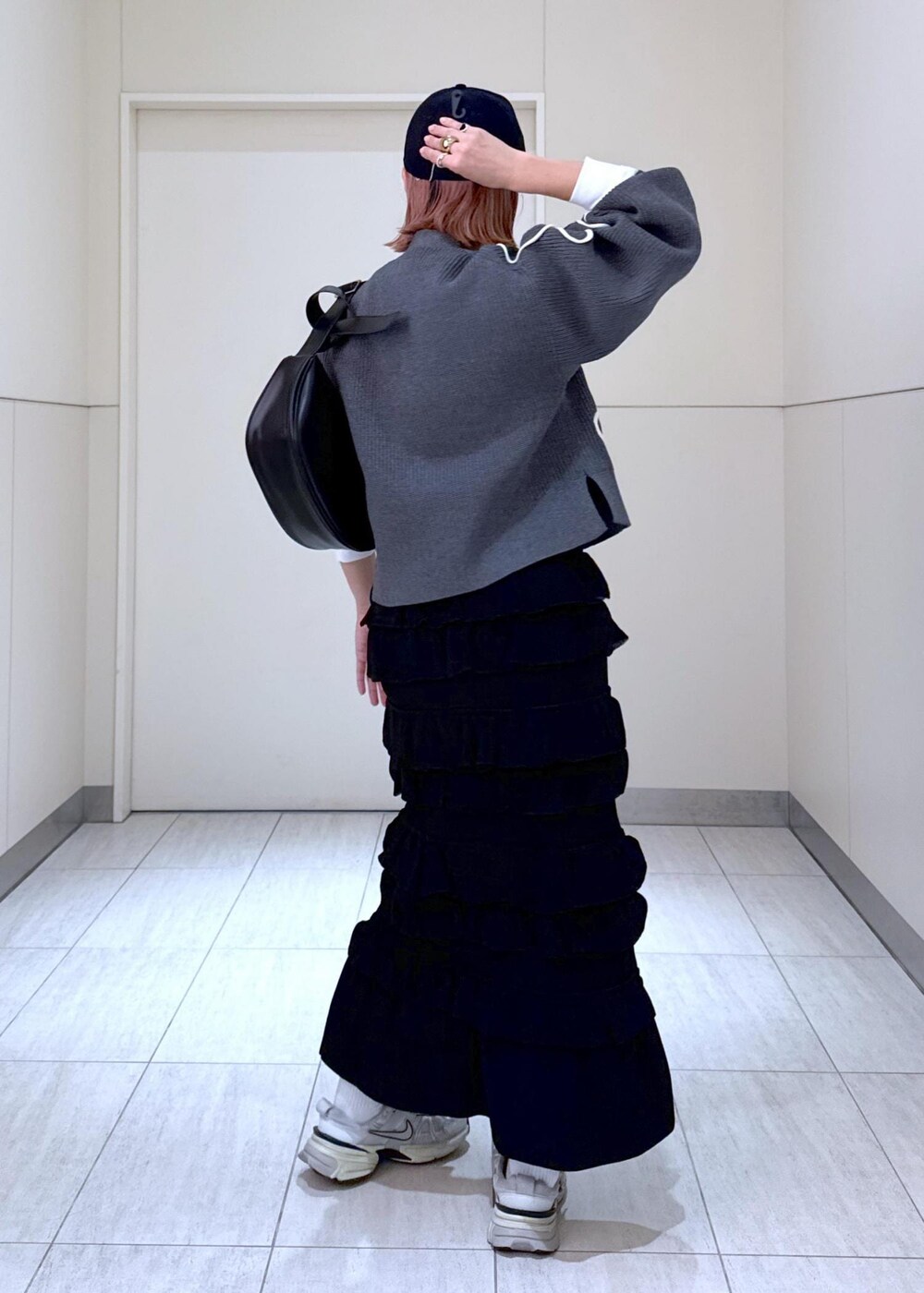 ホワイト系のTシャツ/カットソー、ブラック系のスカート、グレー系のカーディガン/ボレロを着用したレディースの秋コーディネートの4枚目の写真