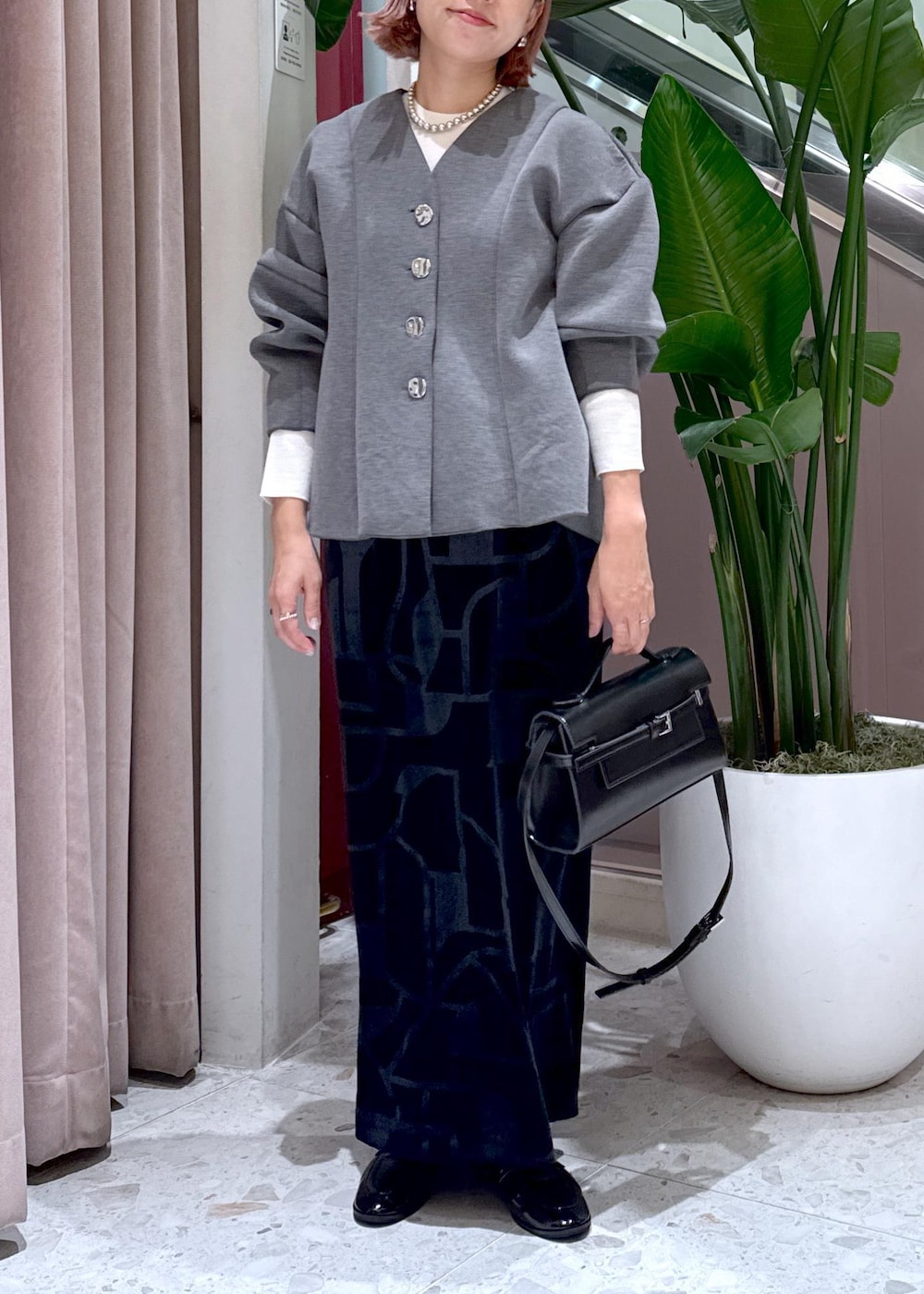 ブラック系のローファー、ブラック系のスカート、グレー系のカーディガン/ボレロを着用したレディースの秋コーディネートの2枚目の写真