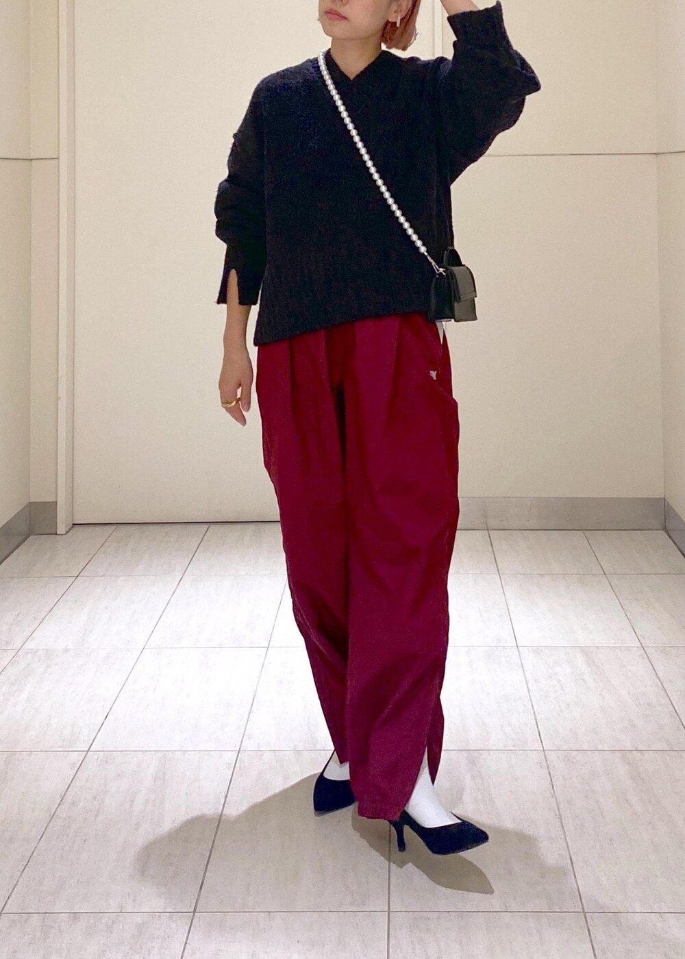 ブラック系のニット/セーター、ブラック系のショルダーバッグ、レッド系のその他パンツを着用したレディースの秋コーディネートの7枚目の写真