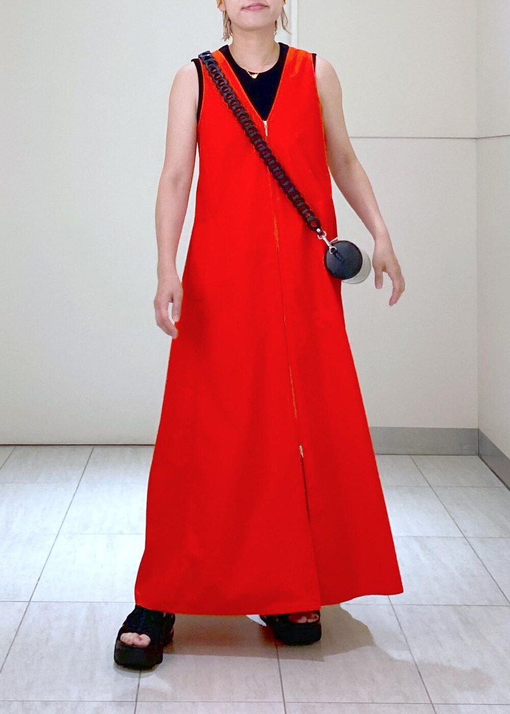 ブラック系のサンダル、ブラック系のドラムバッグ、レッド系のワンピースを着用したレディースの夏コーディネートの3枚目の写真