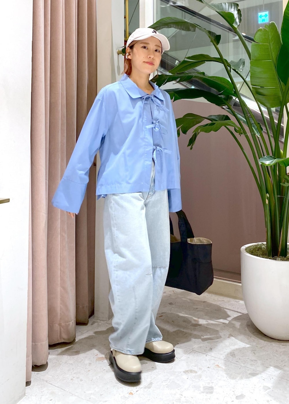 ブルー系のデニムパンツ、ブラック系のトートバッグ、ベージュ系のサンダルを着用したレディースの秋コーディネートの2枚目の写真