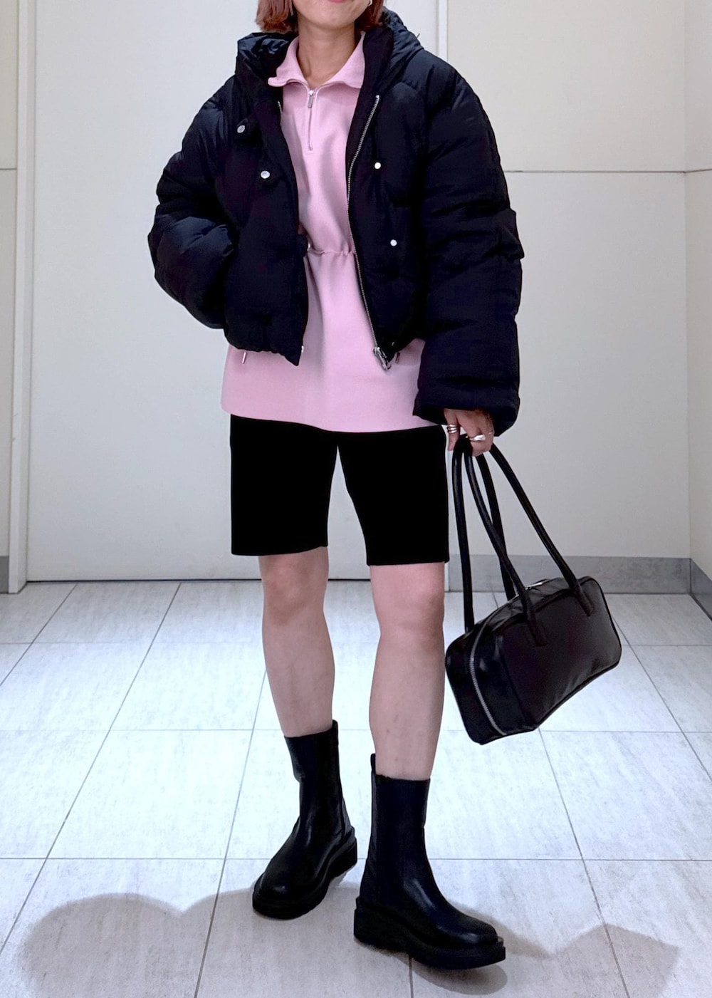 ブラック系のブーツ、ピンク系のその他トップス、ブラック系のボストンバッグを着用したレディースの秋コーディネートの2枚目の写真