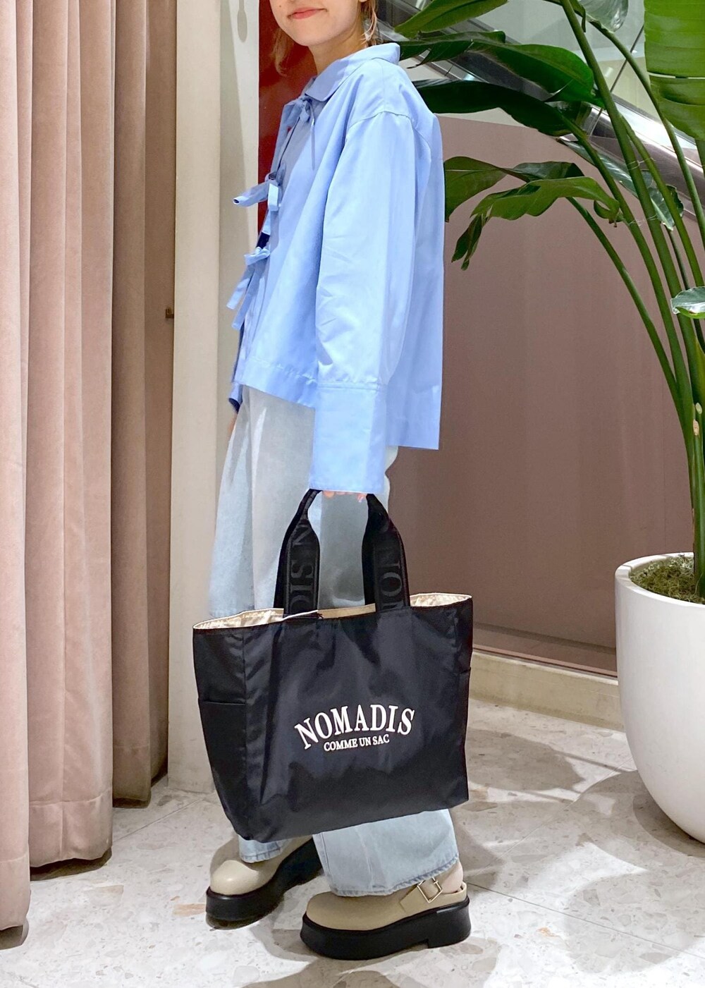 ブルー系のデニムパンツ、ブラック系のトートバッグ、ベージュ系のサンダルを着用したレディースの秋コーディネートの7枚目の写真