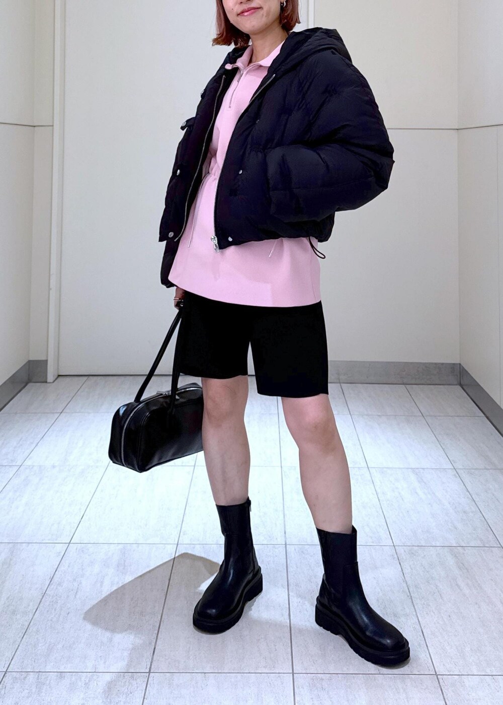 ブラック系のブーツ、ピンク系のその他トップス、ブラック系のボストンバッグを着用したレディースの秋コーディネートの3枚目の写真