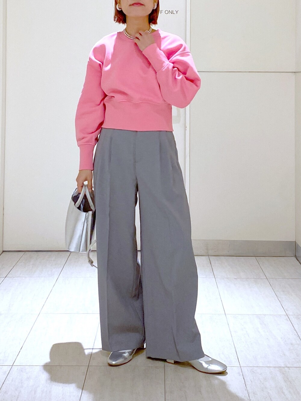 ピンク系のスウェット、グレー系のスラックス、シルバー系のショルダーバッグを着用したレディースの冬コーディネートの2枚目の写真