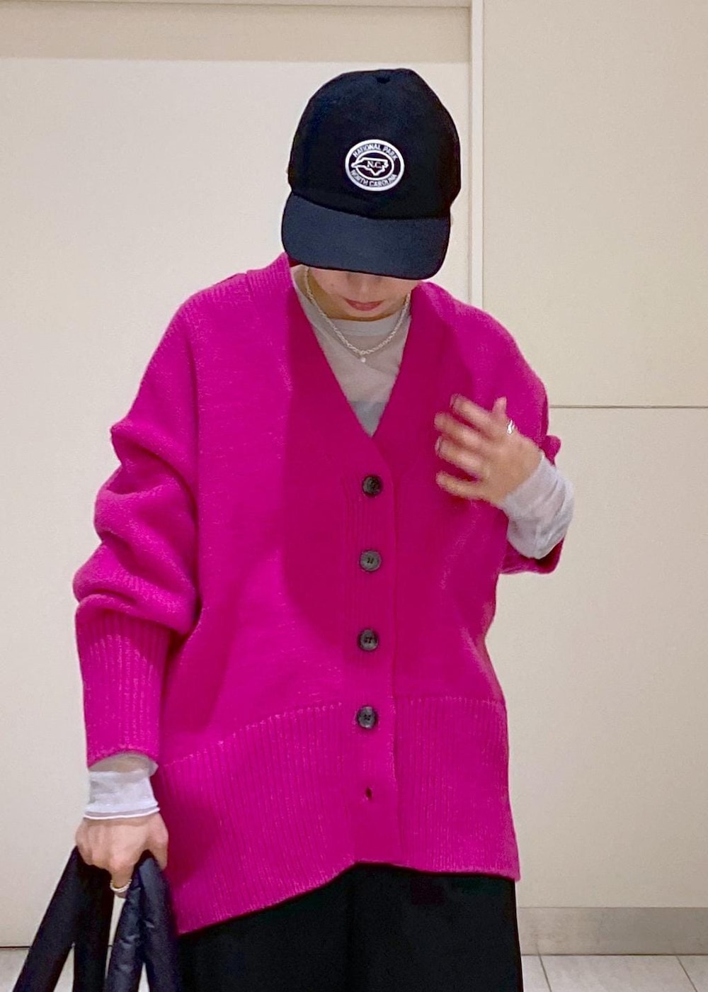 ピンク系のカーディガン/ボレロ、ブラック系のトートバッグ、ブラック系のキャップを着用したレディースの冬コーディネートの7枚目の写真