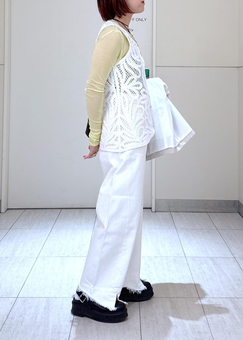 ホワイト系のデニムパンツ、ブラック系のショルダーバッグ、グリーン系のTシャツ/カットソーを着用したレディースの冬コーディネートの8枚目の写真