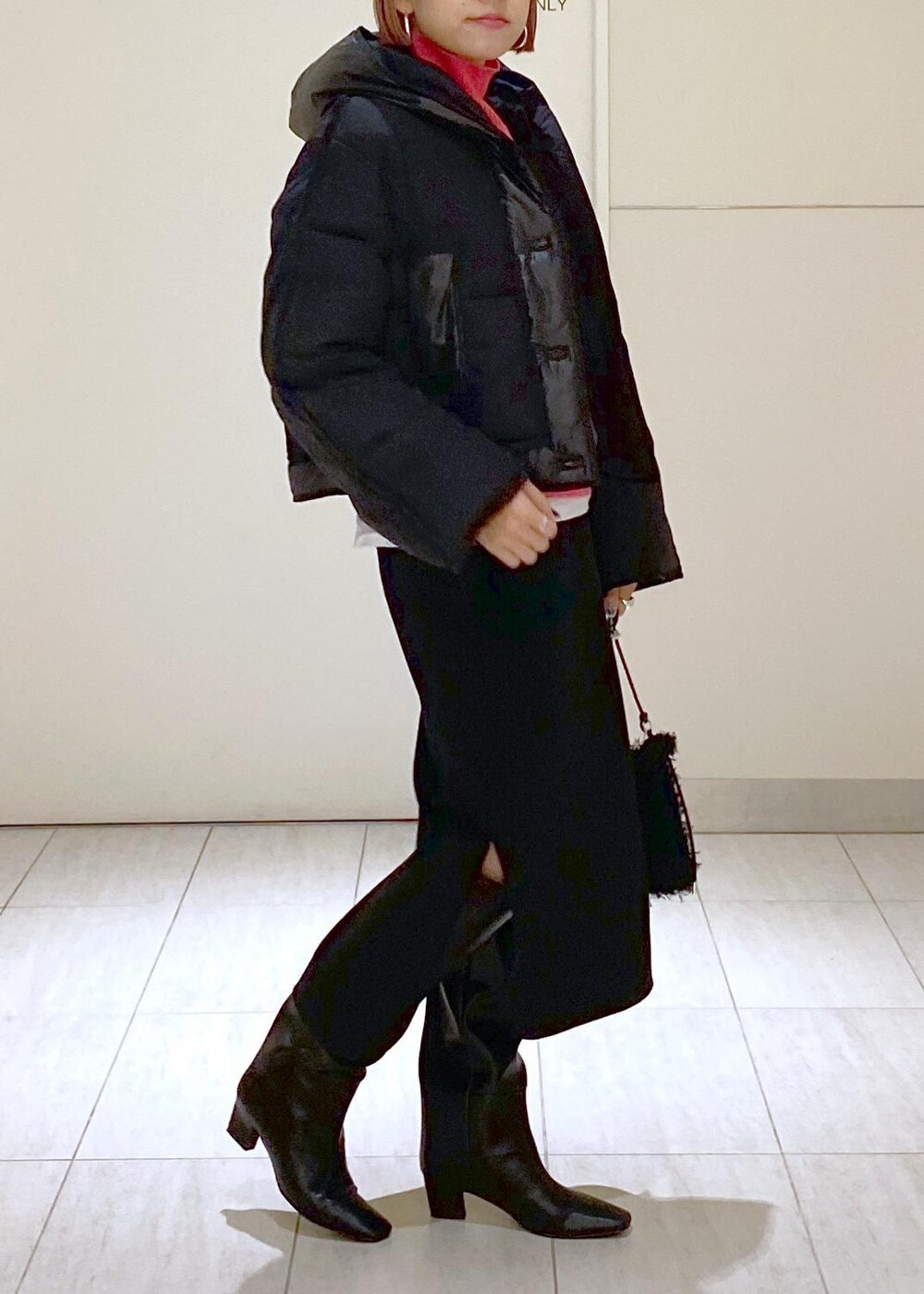 ピンク系のニット/セーター、ブラック系のブーツ、ブラック系のショルダーバッグを着用したレディースの秋コーディネートの2枚目の写真