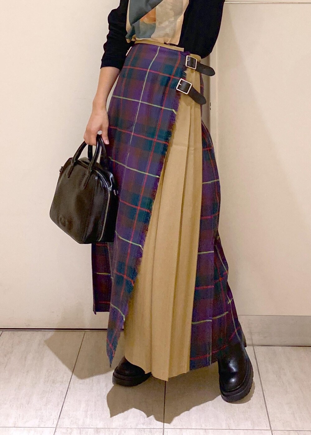 ブラック系のボストンバッグ、ブラック系のブーツ、パープル系のスカートを着用したレディースの秋コーディネートの3枚目の写真