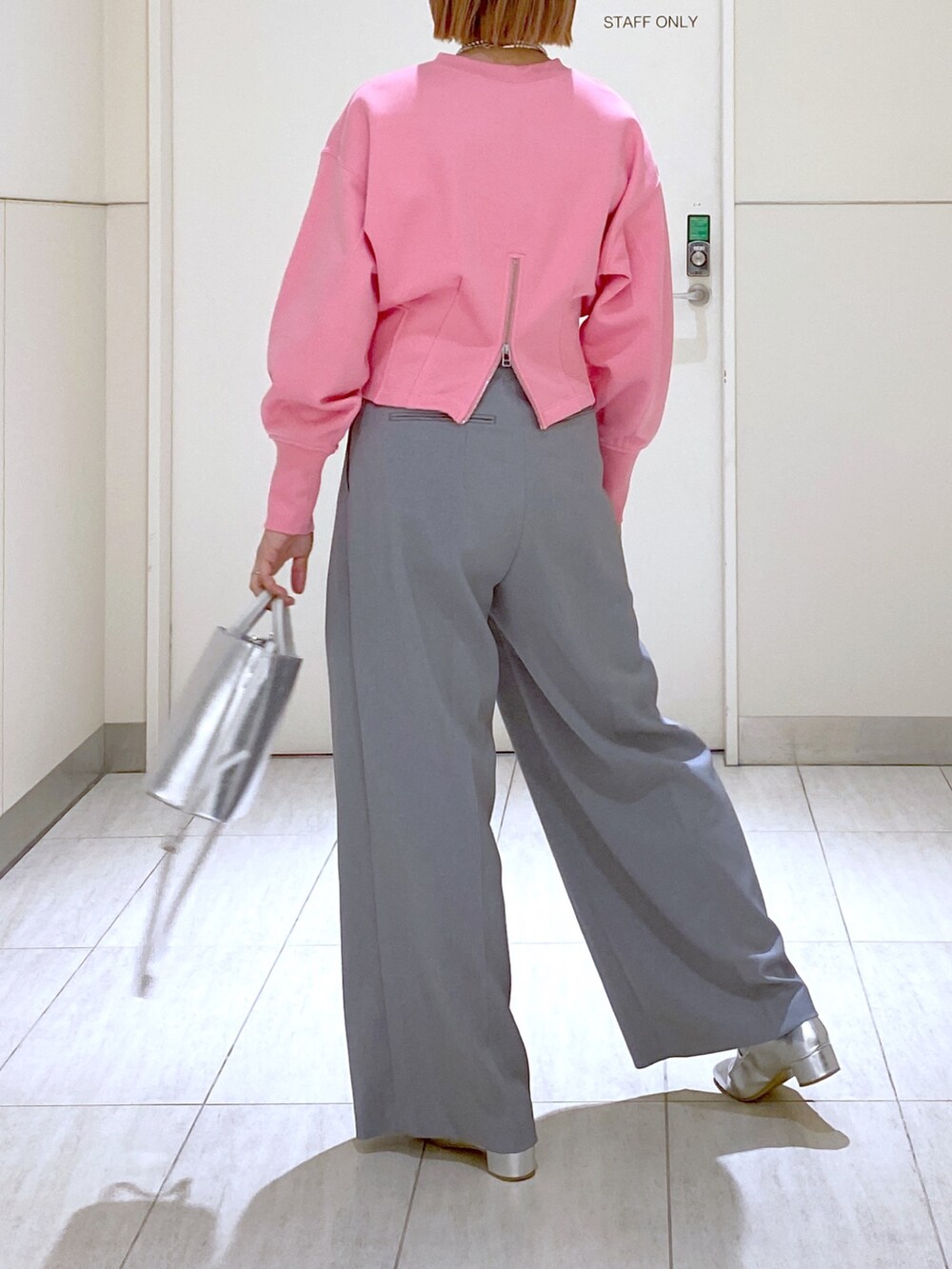 ピンク系のスウェット、グレー系のスラックス、シルバー系のショルダーバッグを着用したレディースの冬コーディネートの6枚目の写真