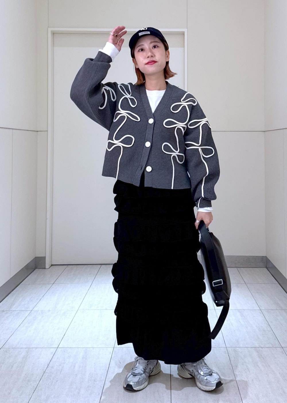 ホワイト系のTシャツ/カットソー、ブラック系のスカート、グレー系のカーディガン/ボレロを着用したレディースの秋コーディネートの10枚目の写真