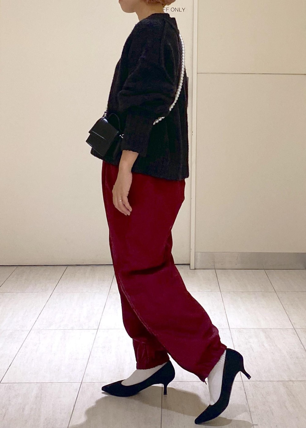 ブラック系のニット/セーター、ブラック系のショルダーバッグ、レッド系のその他パンツを着用したレディースの秋コーディネートの2枚目の写真