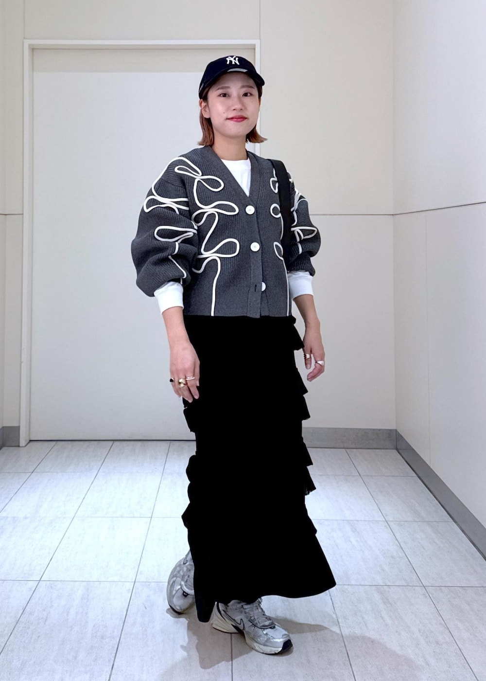 ホワイト系のTシャツ/カットソー、ブラック系のスカート、グレー系のカーディガン/ボレロを着用したレディースの秋コーディネートの9枚目の写真