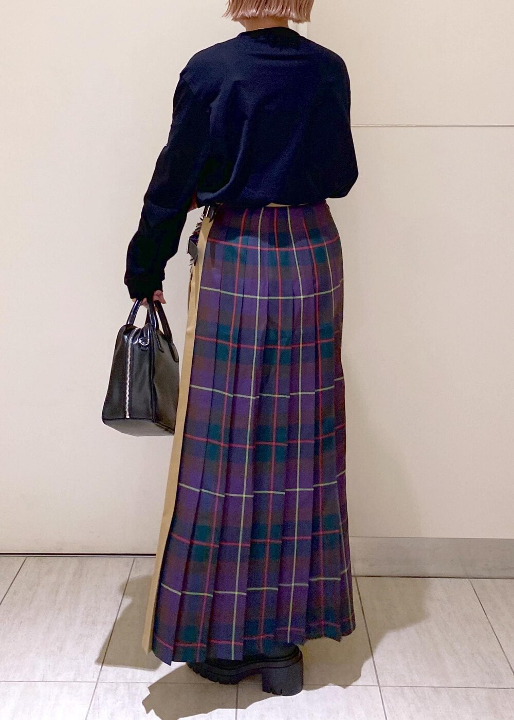 ブラック系のボストンバッグ、ブラック系のブーツ、パープル系のスカートを着用したレディースの秋コーディネートの5枚目の写真