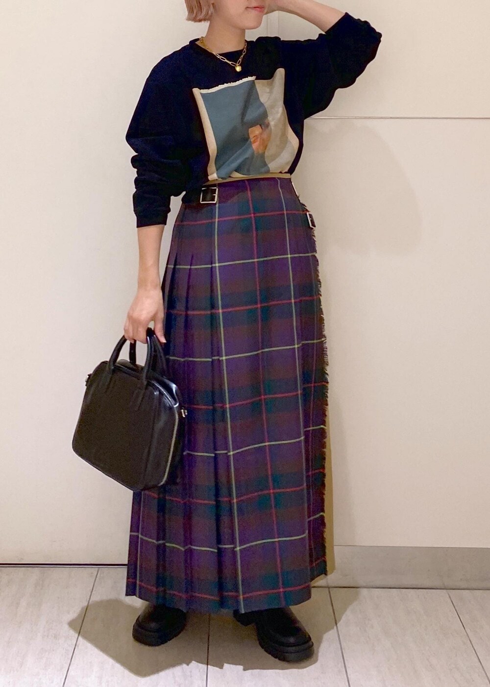 ブラック系のボストンバッグ、ブラック系のブーツ、パープル系のスカートを着用したレディースの秋コーディネートの2枚目の写真