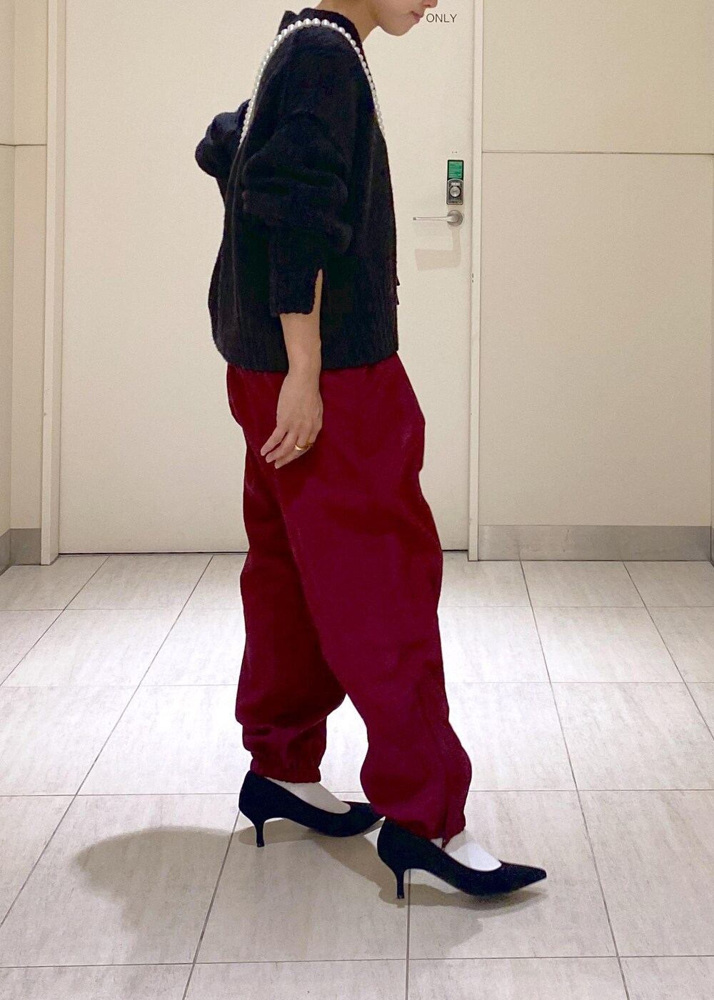 ブラック系のニット/セーター、ブラック系のショルダーバッグ、レッド系のその他パンツを着用したレディースの秋コーディネートの3枚目の写真