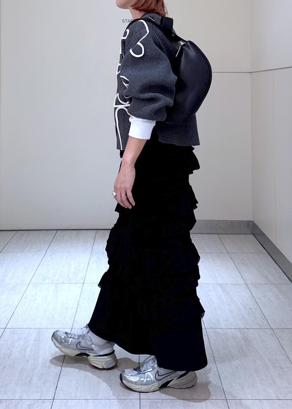 ホワイト系のTシャツ/カットソー、ブラック系のスカート、グレー系のカーディガン/ボレロを着用したレディースの秋コーディネートの5枚目の写真